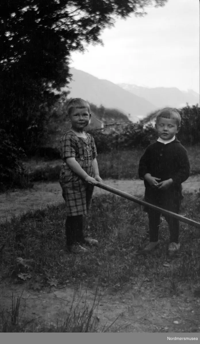 Foto av to gutter ute på en hageflekk, guttene på bildet er to av barnebarna til Georg Sverdrup.
 Bildet er trolig fra Solbakken i Nesset kommune
 i Møre og Romsdal,
 Datering er også usikkert, men trolig omkring 1920 til 1939. Fra Nordmøre museums fotosamlinger.
