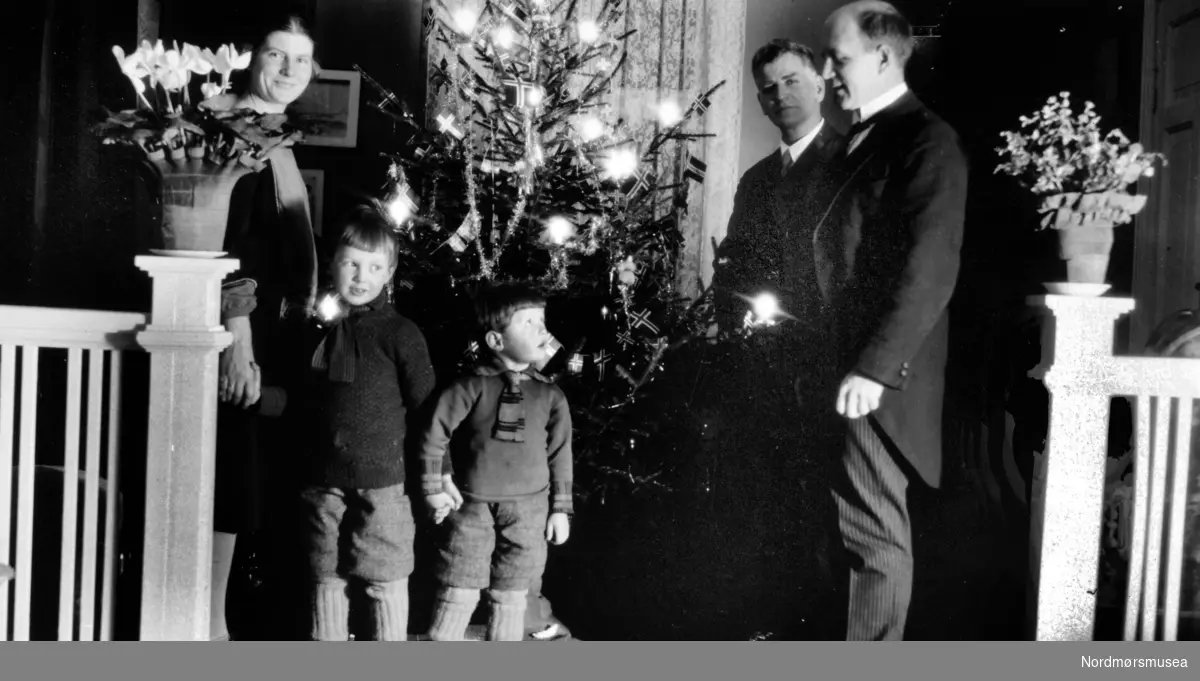";Ved nytårstider - Fra stuen her."; Trolig Georg Sverdrups familie i Kristiansund, som trolig også er fotograf. Datering er sannsynligvis fra perioden 1930 til 1939. nyttårsfeiring, familie, barn, menn, dame, kvinne, juletre, julepynt,
 Fra Nordmøre Museums fotosamlinger.

