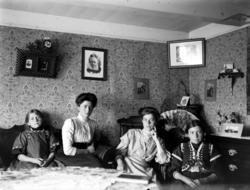 To kvinner og to jenter sittende i en dagligstue. De er trol