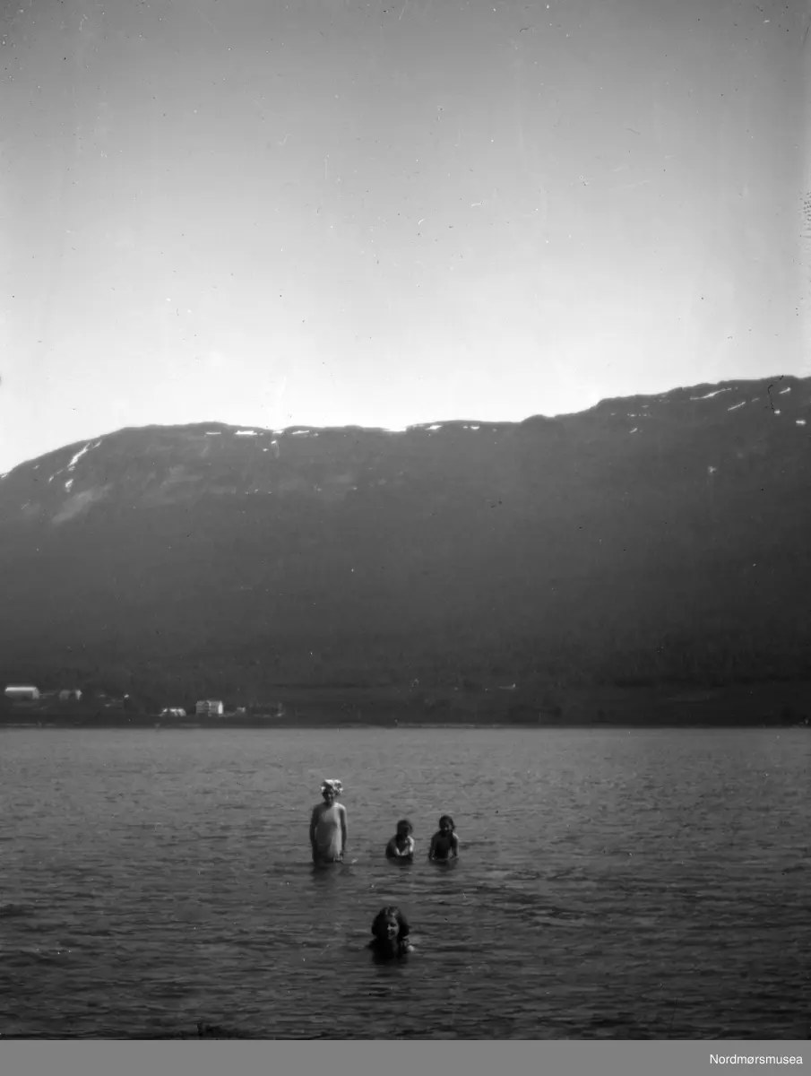 Tre barn og en kvinne er ute å bader i sjøen, trolig i Eidsvåg og Nesset kommune. Kvinnen og barna er muligens fra Sverdrupfamilien/slekten, eventuelt fra deres bekjentskaper. Datering er ukjent, men trolig omkring 1920 til 1939. Fra Nordmøre museums fotosamlinger. EFR2015