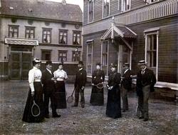 Foto av en gruppe menn og kvinner, samlet til en tenniskamp 