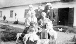 En gruppe mennesker med gårdsdyr oppstillt foran et langhus 