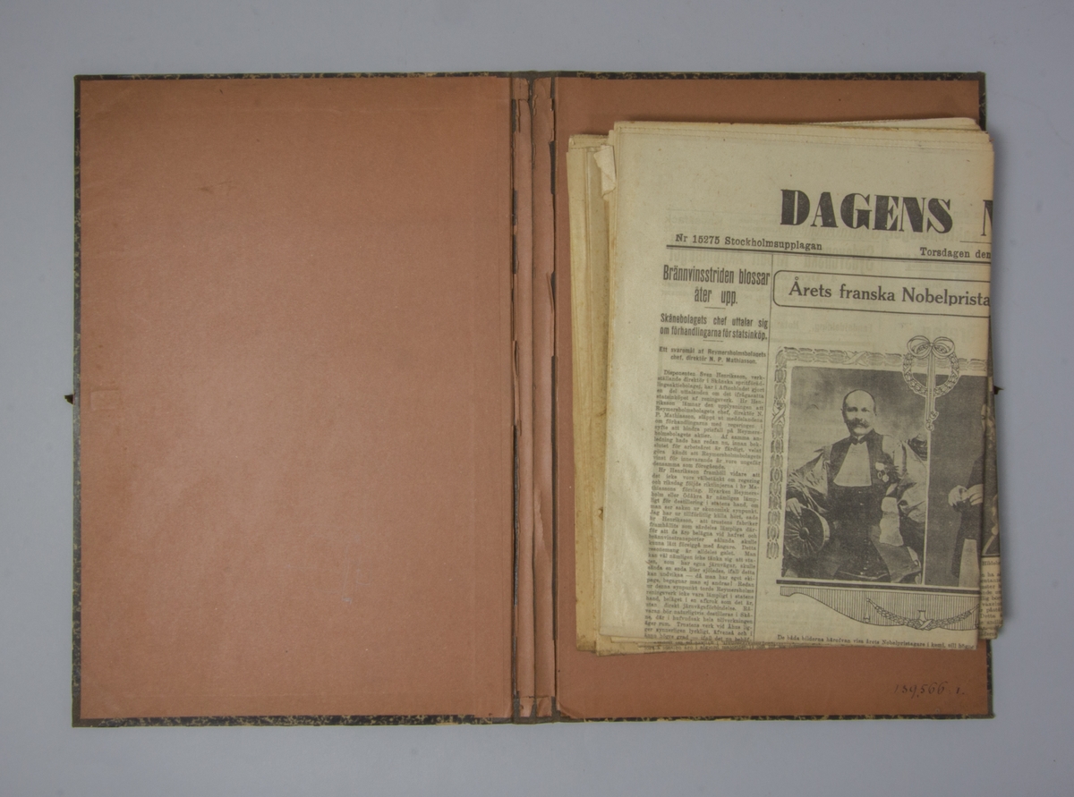 Portfölj av marmorerad papp. Sammanhållen med knytband. Rygg av svart linne. Innehåller enbart flera exemplar av Dagens Nyheter från 1912.