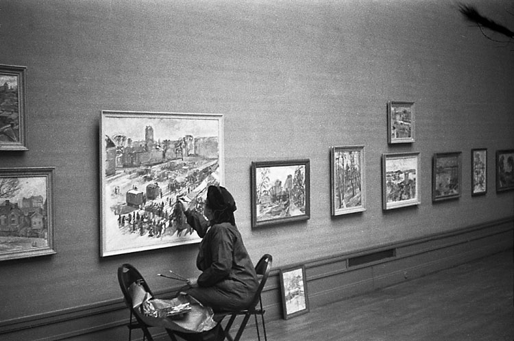 Utställningsarbete på Smålands museum. Foto från Ingegerd Beskows (1887-1978) utställning. 
Konstnärinnan målar något på en av tavlorna.