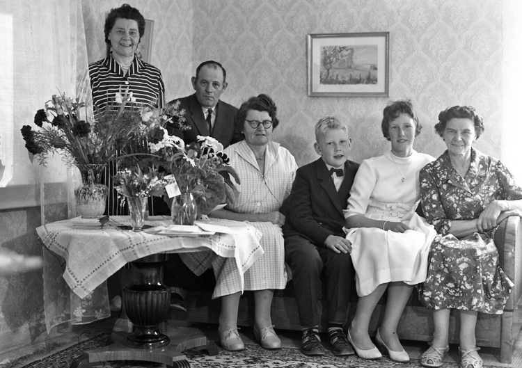 Foto av en ung kvinna i vit konfirmationsklänning, tillsammans med sin familj.
De sitter i ett vardagsrum, vid ett bord med blommor på.
Konfirmand 1959. 
Christina Nilsson, Forsdala Gård, Hjortsberga. (1944-2014). Konfirmerad i Hjortsberga kyrka pingstdagen 17 maj 1959. Familjefoto 1959.
Födelsedag – konfirmation. Forsdala, Gård, Hjortsberga.
Fr.v. Hildur Zandin, f. Johansson, Moheda (1901–1986).  Jubilaren Lennart Nilsson 50 år, (f. 5 juni 1909 –1972). Hustru Margit, f. Johansson, Moheda, (1912–1995). Barnen Mats-Ola Nilsson, (1949 - ), Christina Nilsson, (1944-2014), Svea Johansson, (1902-1989). Hildur och Svea var systrar till Margit.