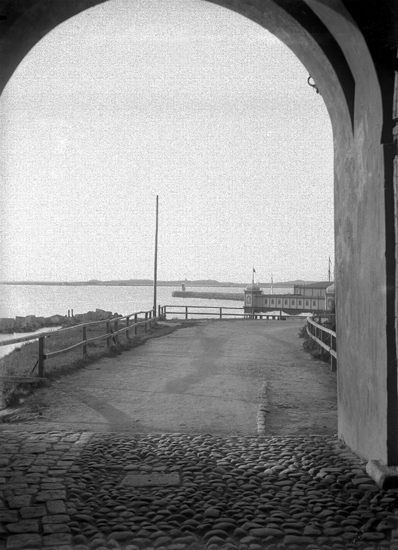 Vy från en av fästningsportarna mot hamnen och kallbadhuset, som skymtar till höger.
