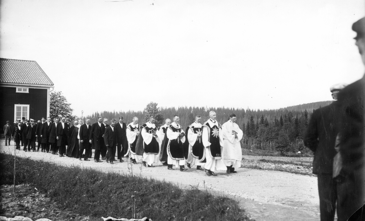 Från invigningen av Gruvbergets kapell den 4 juli 1927. Präster och kyrkvärdar på väg till invigningen av kapellet i Gruvberget. Den ljuse till vänster i första ledet är pastor Härdelin från Bollnäs, till höger i andra paret går komminister Lennart Tillgren från Bollnäs. Mitt bland kyrkvärdarna går ärkebiskop Nathan Söderblom med sin biskopsstav.