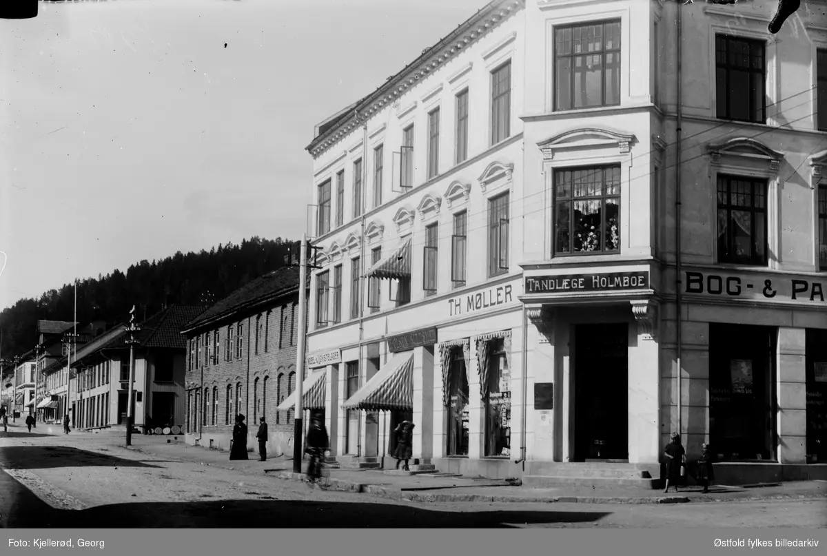 Gateparti fra Storgata i Gjøvik, Møbel. og ligkistelager. Gullsmed H. Olsen (Hans Oskar Olsen), Th. Møller Bog & Papir. Kontoret til tannlege Holmboe.