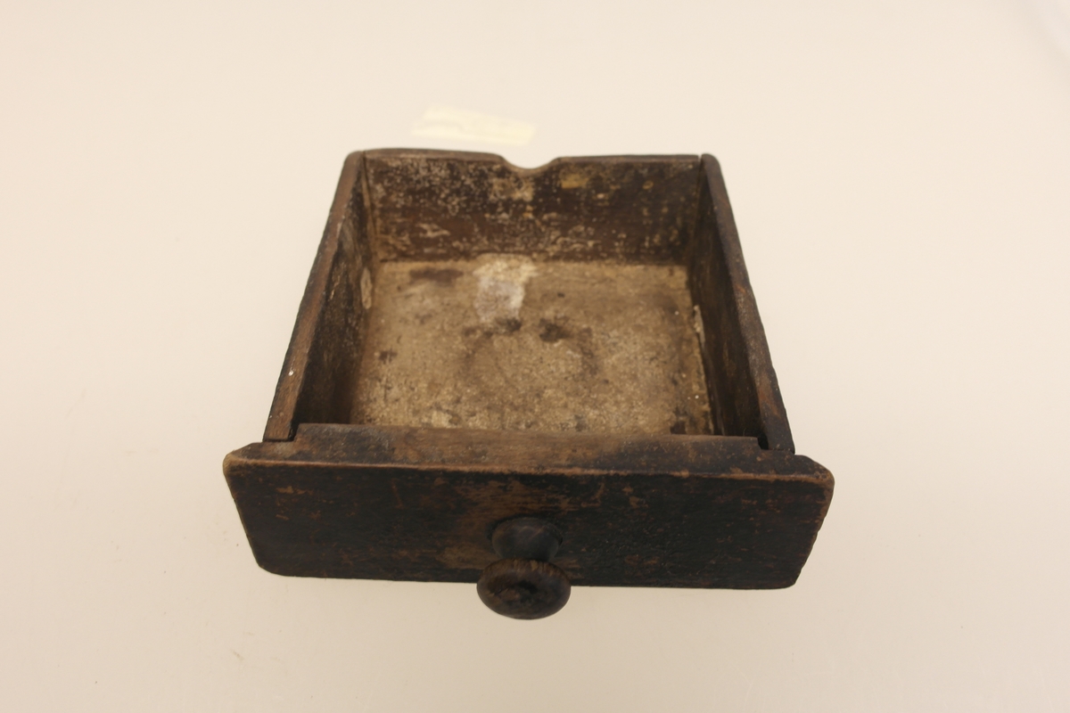 Kaffekvern (a og b) i tre, jern og messing. 
a) Kvadratisk kasse med topplate og bunnplate. Sveiv som går ned til innsatt tannhjul, som kverner kaffebønnene. Klokkeformet deksel som kan åpnes med en klaff som skyves til siden. Messingskilt med stempel.
b) Skuff som samler opp den malte kaffen. Stiftet i hjørner og bunnplate.