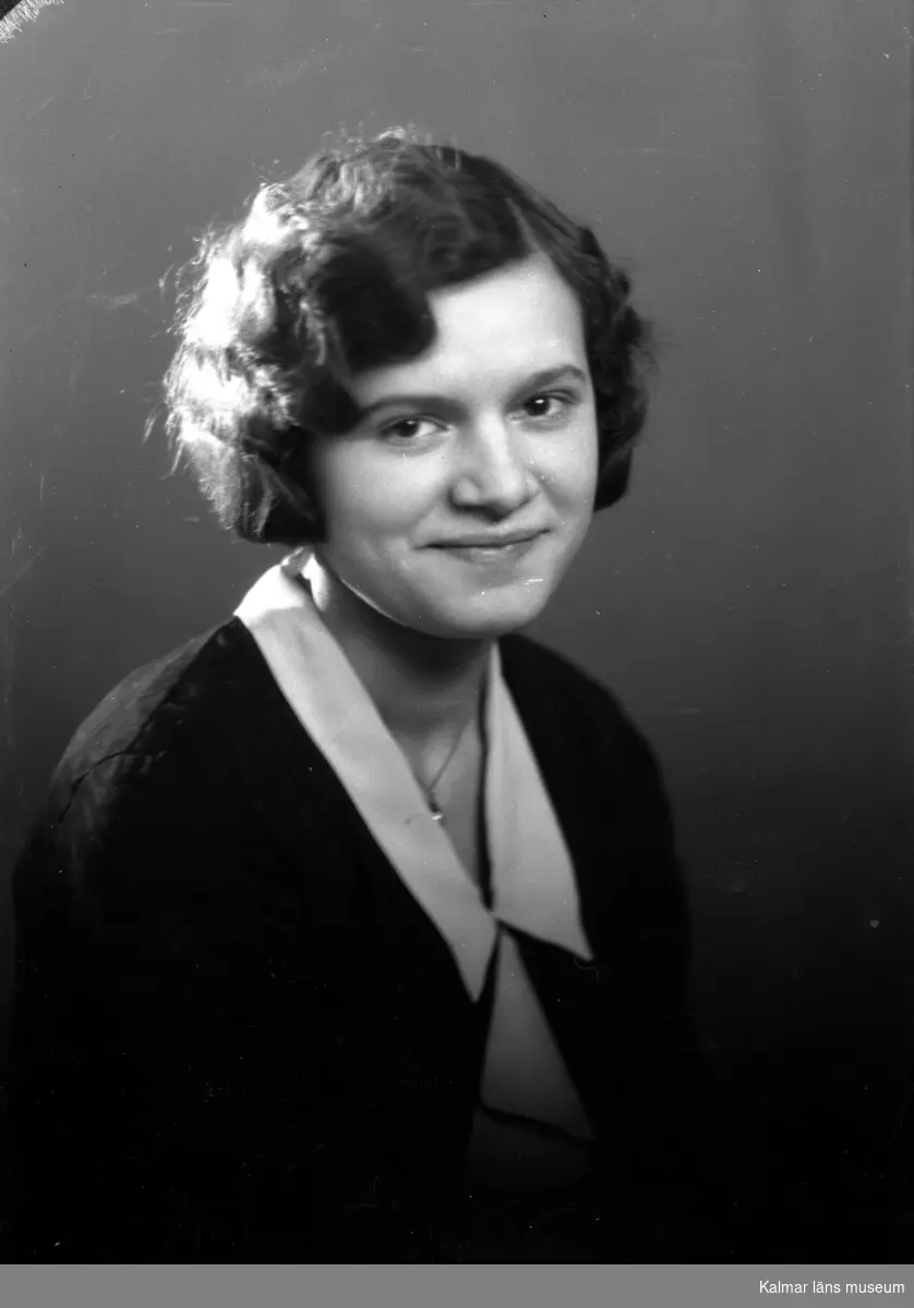 Ateljébild på en kvinna i halsband med hänge och en blus. Enligt Walter Olsons journal är bilden beställd av fröken Margit Nilsson ifrån Kläckeberga.