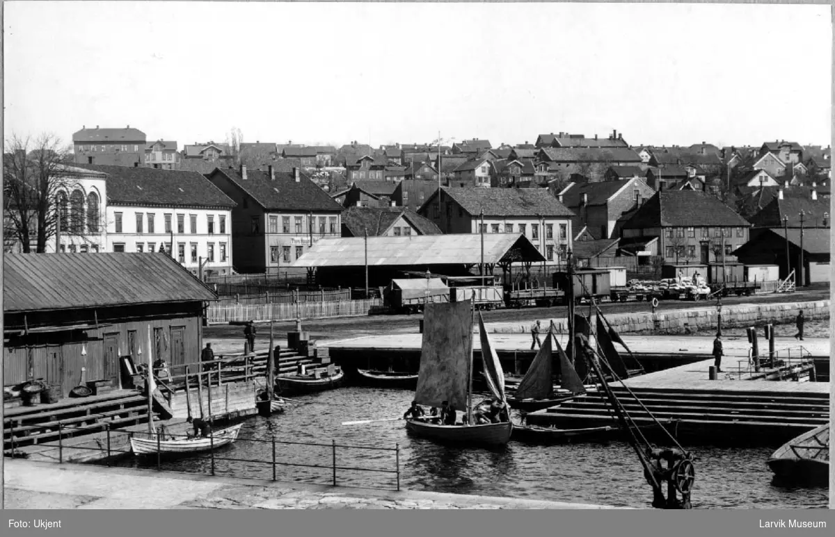 Byprospekt, bebyggelse, Larvik, sjøsiden, jernbanen, Storgata med Festiviteten og Thora Hansens hotell, småbåter på havnen, noen med seil.