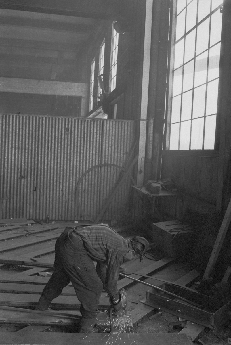 Ekensbergs varv 1970. Varvsarbetare med slipmaskin i stora plåthallen.