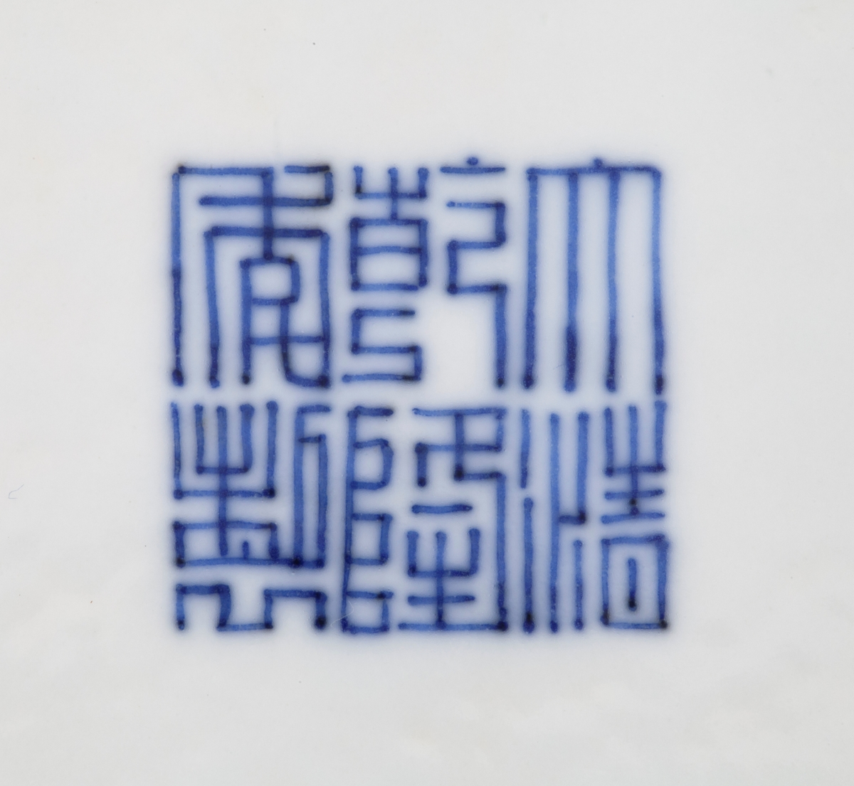 På skålens cavetto finner vi de åtte taoistemblemene som representerer de åtte udødelige (anbaxian). Symbolene representerer blant annet langt liv, velstand og forandring. Symbolene i rekkefølge er: (1) Flaskegresskaret representerer Li Tieguai og inneholder magiske medisiner. (2) Til høyre for flaskegresskaret finner vi et sverd som representerer Lu Dongbin, barberernes og de lærdes skytshelgen. (3) Den neste er en bambustromme med stikker som representerer Zhang Guo, symbol for høy alder og langt liv. (4) En vifte som representerer Zhongli Quan, de åtte udødeliges leder. Viften vekker de døde til live og symboliserer gjenoppstandelse, forandring og langt liv. (5) Lotus, som representerer He Ziangu, den kvinnelige vismann som assisterer i husarbeid. (6) Fløyten representerer Han Xiangxi, musikerne og blomsterbindernes skytshelgen, et symbol for vekst og harmoni. (7) Blomsterkurven representerer Lan Caihe, blomsterbindernes helgen og er et symbol for villedende forlystelse. (8) Kastanjetter, som representerer Cao Guojiu, teaterskuespillernes skytshelgen.

I speilet på skålen ser vi en sentralisert, sirkulær blomst omgitt av fersken og lotusranker. Cavetto og speil innringes  av konsentriske ringer i blå underglasur. Utsiden av skålen er dekorert med blomsterranker, konsentriske ringer i blå underglasur og en ranke med trepass nederst ved foten.