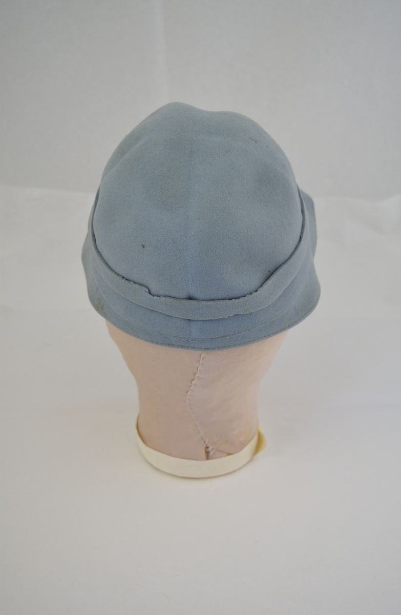 Rund hatt med brem som smalner på hattens bakside. Påsydd bånd med sløyfe. Form: bolleform