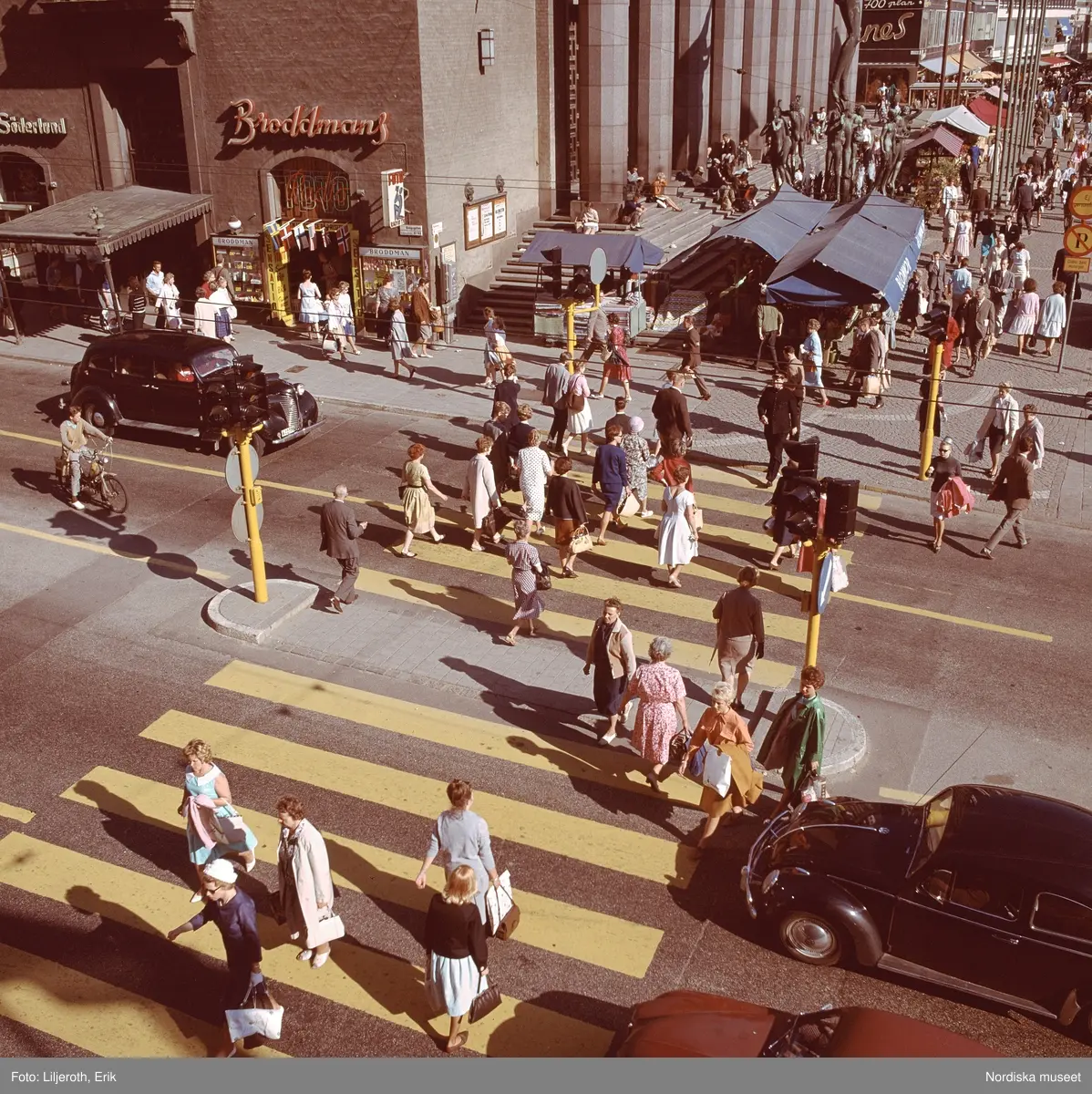 M&auml;nniskor och bilar i v&auml;nstertrafik vid &ouml;verg&aring;ngsst&auml;lle, Kungsgatan intill H&ouml;torget och Konserthuset, Stockholm.