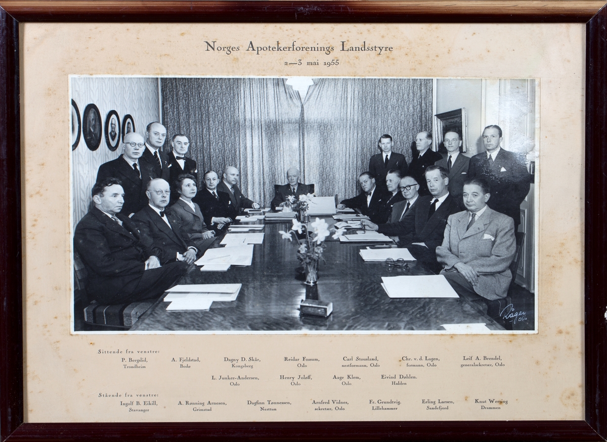 Gruppefoto av møtedeltagere, 17 menn i dress og 1 dame, sittende og stående.