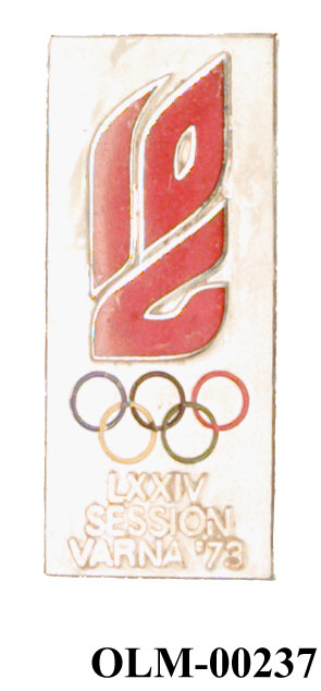 Rektangulært hvitt merke med et ornament i rødt øverst,  olympiske ringene i farger og innskriften LXXIV Session Varna'73 nederst.