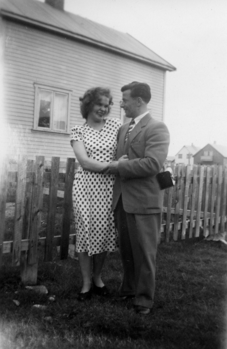 Pent antrukket par foran hus i Vadsø. Kvinnen er Ragnhild Henriksen. Huset er det første som ble bygget i August Trastis gate. Bildet er tatt rett etter huset stod nybygd i 1947-1948.