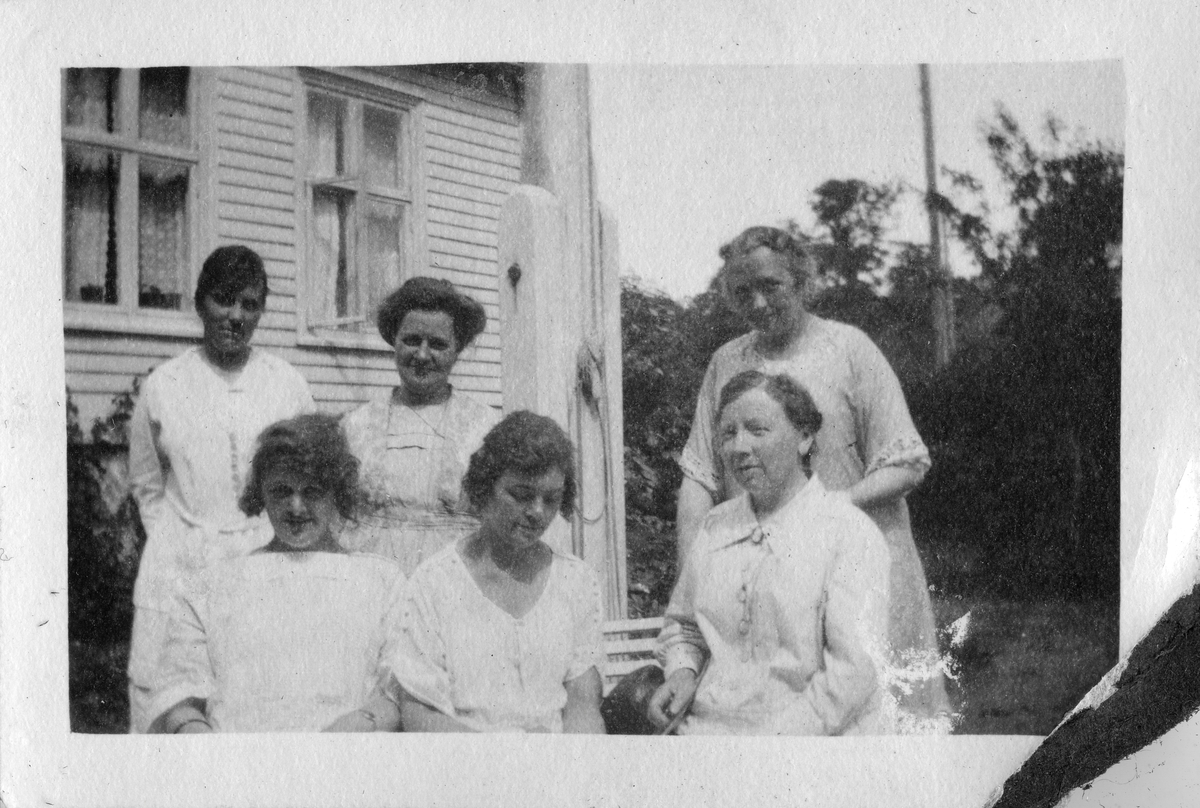 Gruppe mennesker på en benk i hagen ved Grand Hotel, Lillesand 1921. Bildetekst: "Lillesand, sommere