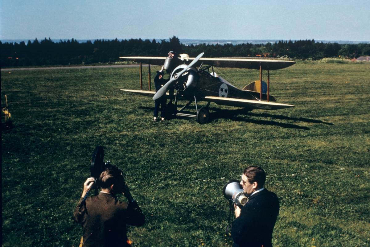 Klargöring av flygplan FVM Tummeliten märkt nummer 3656 vid flygdagarna på Malmen 1-2 september 1962, vid firande av militärflyget 50 år. I förgrunden står en man vid en filmkamera samt en speaker med megafon.