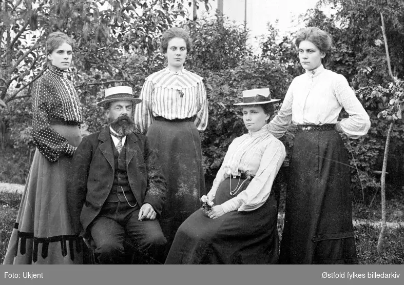 Gruppe i hage i Rømskog, ukjent hvor, ca. 1905-10 (?)

Foran fra venstre: 
Julius Tukkun, Dorthe Tukkun. 

Bak fra venstre: 
Maren Trandem, Olga Evenby, Tora Tukkun.