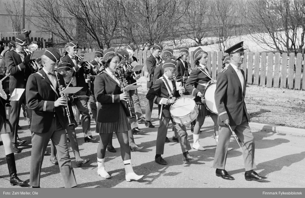 Vadsø 17.5.1969. Vadsø skolemusikk leder an i 17.mai toget. Foran sees dirigenten, skarptromme, stortromme og flere med klarinetter og trompter.  Fotoserie av Vadsø-fotografen Ole Zahl-Mölö.