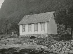 Motiv av et stuehus mellom fjæra og fjellet på Alnes. (gamme