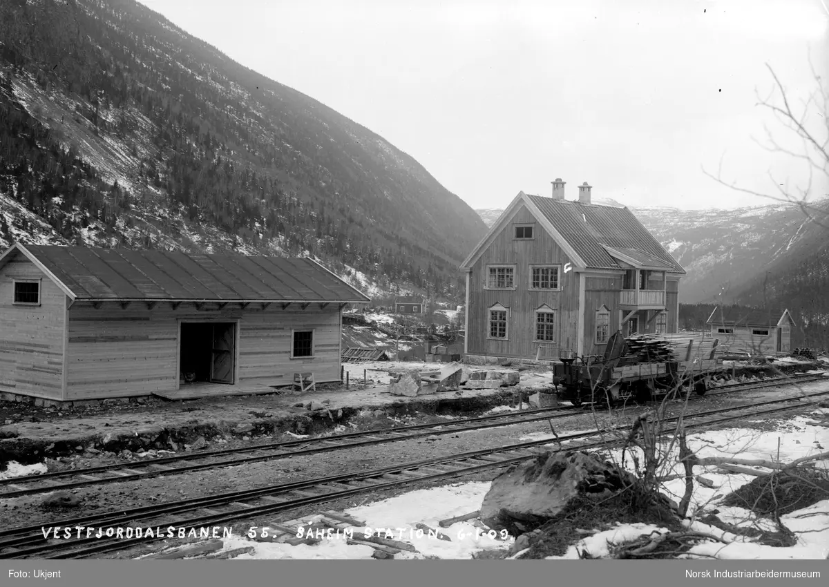 Såheim Stasjon (Rjukan stasjon) og pakkhus ferdig bygget. Lagerbygg eller garasje på stasjonens østside. To åpne kassevogner stående på jernbanesporet.
