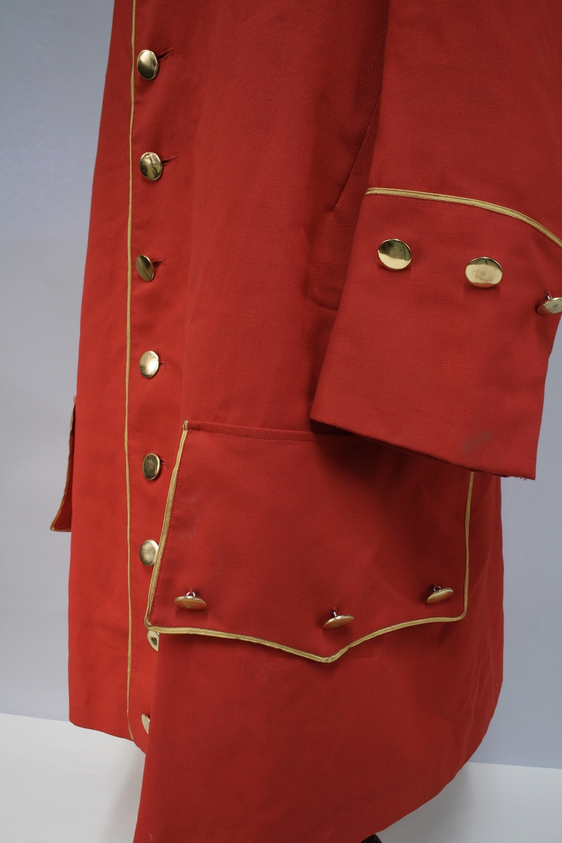 Rød frakk med 11 blanke gullknapper, 3 knapper på hvert erme og lomme. Gul passpoil ned fronten, rundt lommeklaffene og ermet. Kort, oppstående krage. Sort lue med lange flapper. Bukse med belte.