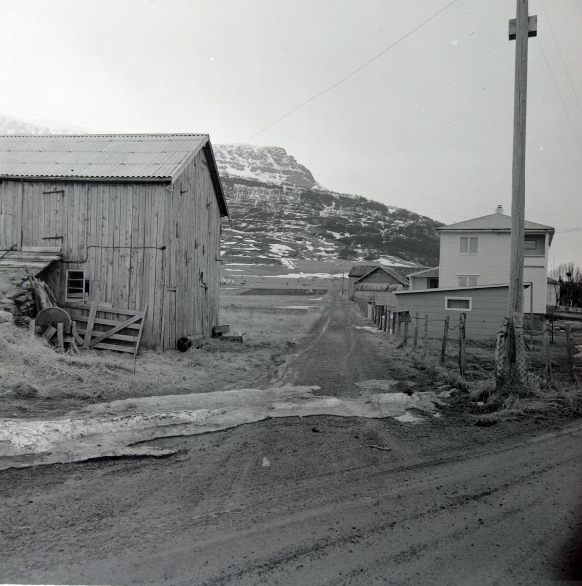 Gårdsbygninger ved snuplassen på Sørrollnes, fjell i bakgrunnen.