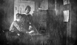 Foto av to kvinner rundt en telefonsentral. Foto fra Kristia