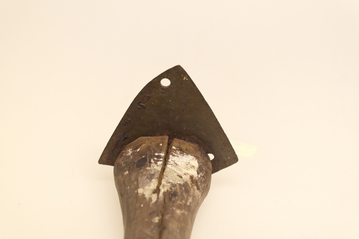 Malerskrape med skaft av tre og skrape i jern. Gjenstanden er hjemmelaget. Jernet var opprinnelig kniven til en slåmaskin.