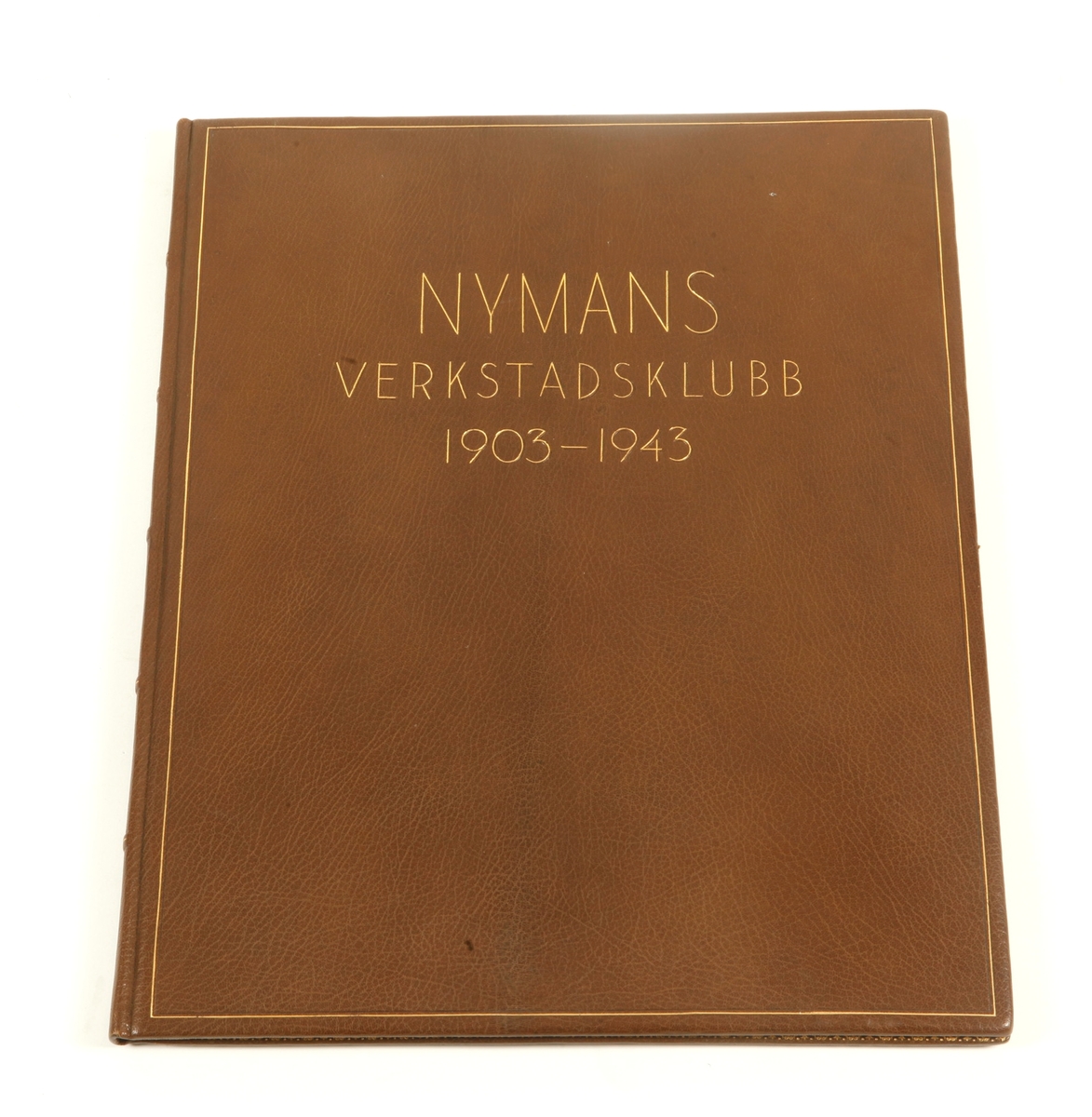 Festskrift i brunt skinnband med text i guld: NYMANS VERKSTADSKLUBB 1903 - 1943, med akvarellerade tuschteckningar, maskinskriven text och inklistrade fotografier. Signerad: L. Spove.L.
