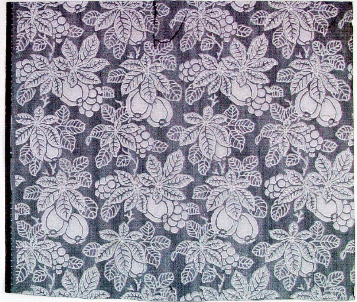 Tätt ytfyllande mönster bestående av äpple, druvor och blad över litet rutmönster. Tryck i vitt på ett grått genomfärgat papper.