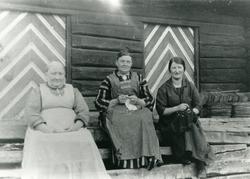 3 kvinner på trappa utenfor en tømmerbygning (stabbur?). En 