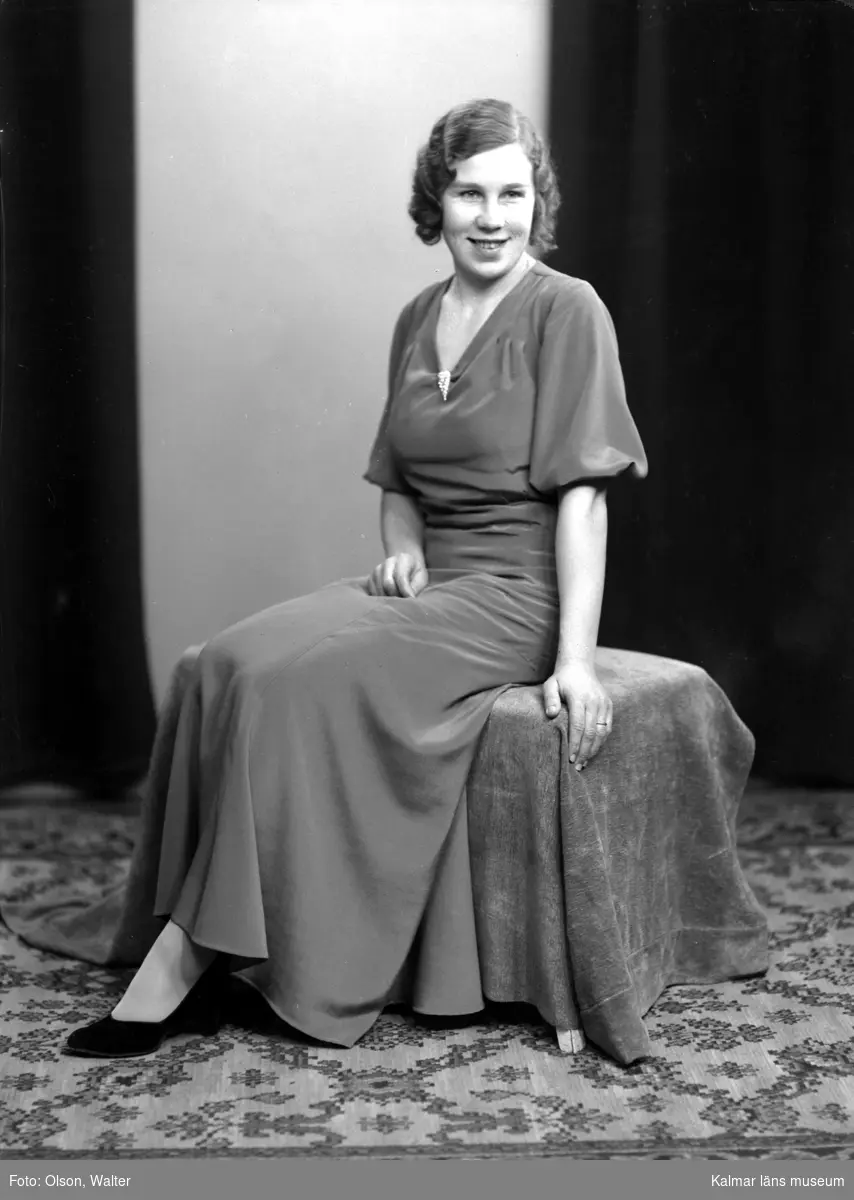 Ateljébild på en kvinna i aftonklänning. Enligt Walter Olsons journal är bilden beställd av Astrid Andersson.