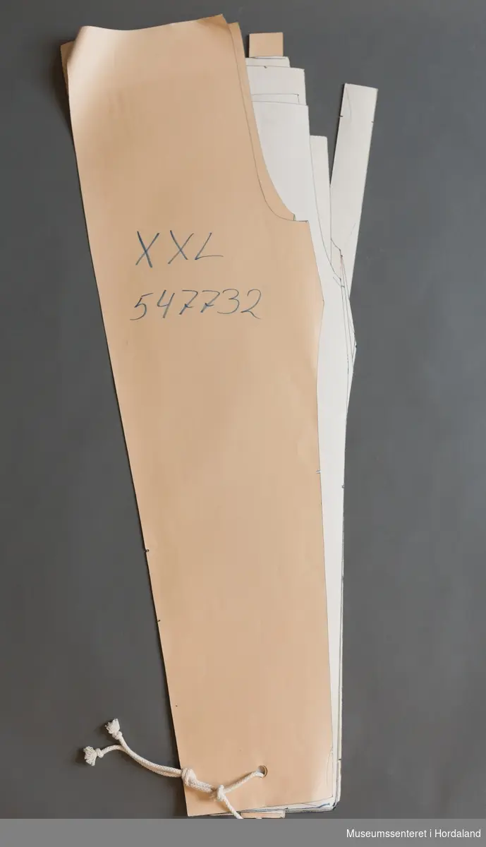 Mønsterskantar i papp, brukt til å skjere ut ulike delar av plagg i klesproduksjon. Desse er til ei bukse, XS-XXL. Art. nr. 547732.