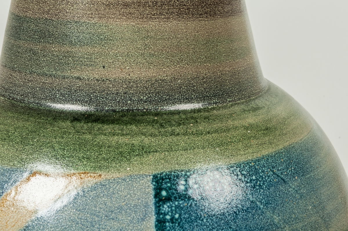 Vas modell D50, formgivare Ewald Dahlskog för Bo Fajans 1930. Vasen formgiven för och visad första gången vid Stockholmsutställningen 1930, i företagets monter. Bukig med snett avsmalnande hals, som slutar med bred platt överkant. På sidorna motiv med två stiliserade fantasidjur med vingar i rött och vitt. I övrigt färgfält i grått, blått, grönt.