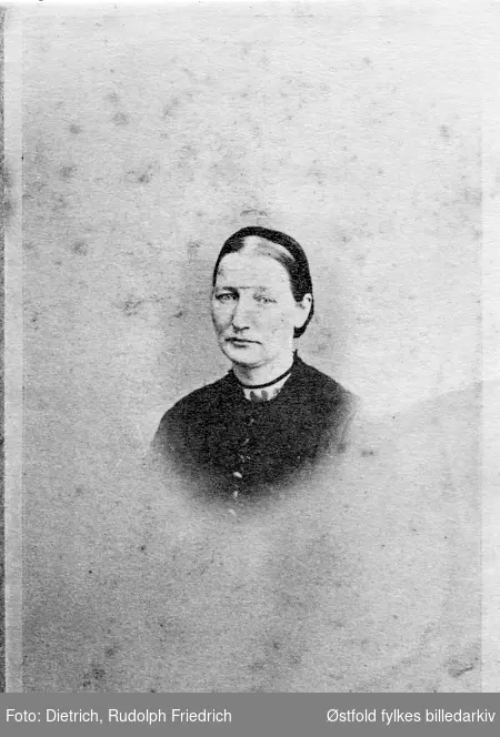 Karen Olsdatter f. 1835  fra Olseng nordre i Skjeberg, gift Isaksen, Fredrikstad. Vignettert portrett, visittkort. 
Foreldrene til Karen var Ulrik Kristiansen Olseng og Inger Johannese Arnesdatter Kjenner, Rakkestad.