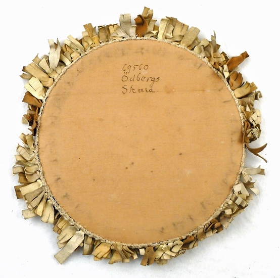 Lamjpmatta, rund, blå sammet i mitten, gråvita skinnremsor trädda på en virkad kant runtom, baksidan av ljust brunt bomullstyg, pappskiva inuti. Lika som 69.559.
 
Auktion 1933-05-13