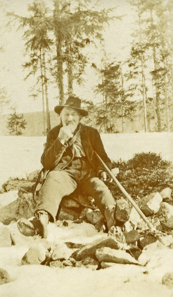 Mann sittende i steinrøys ute i snøen; Ljøstad-Børe (Børe Gjermundsen Langtjernåsen) (13/9 1827 - 18/3 1925)