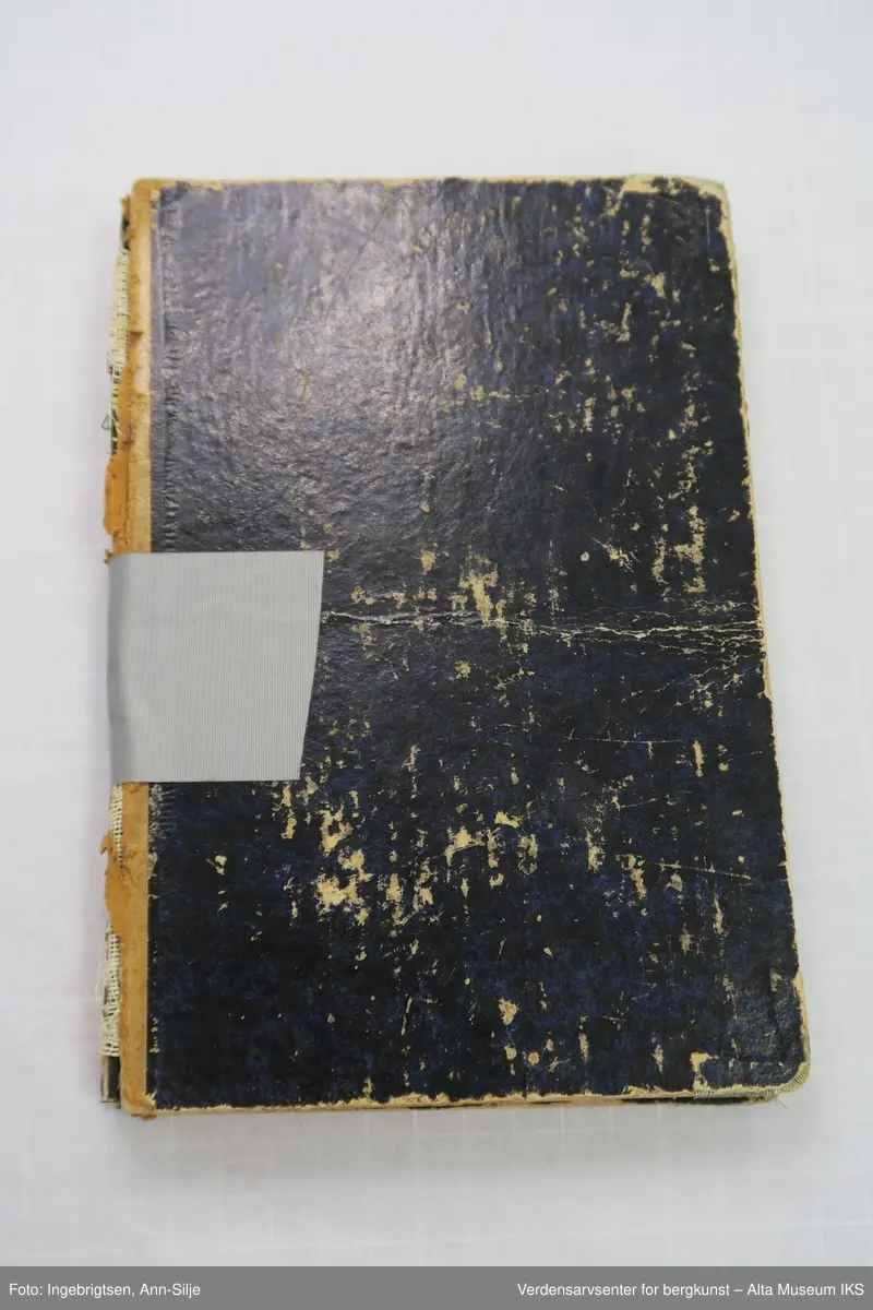 Bok med svarte permer. Ryggen på permen er ødelagt og permene blir holdt sammen av en grå tape.