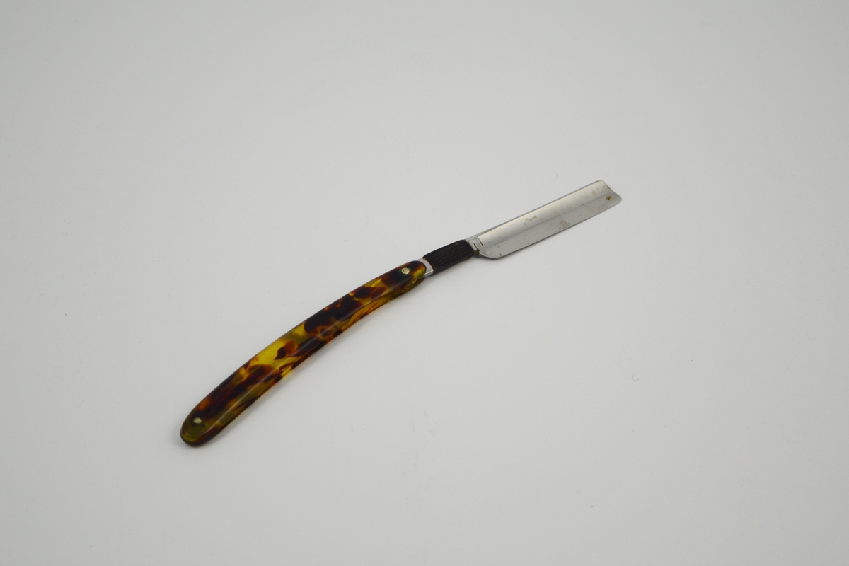 Form: Åpent hylster hvor barberkniven stikkes ned. Knivblad: skrått kuttet profil og buet, meget kvass egg. Skaft meget kort (2.1 cm) tversgående riller. Åpen tange.