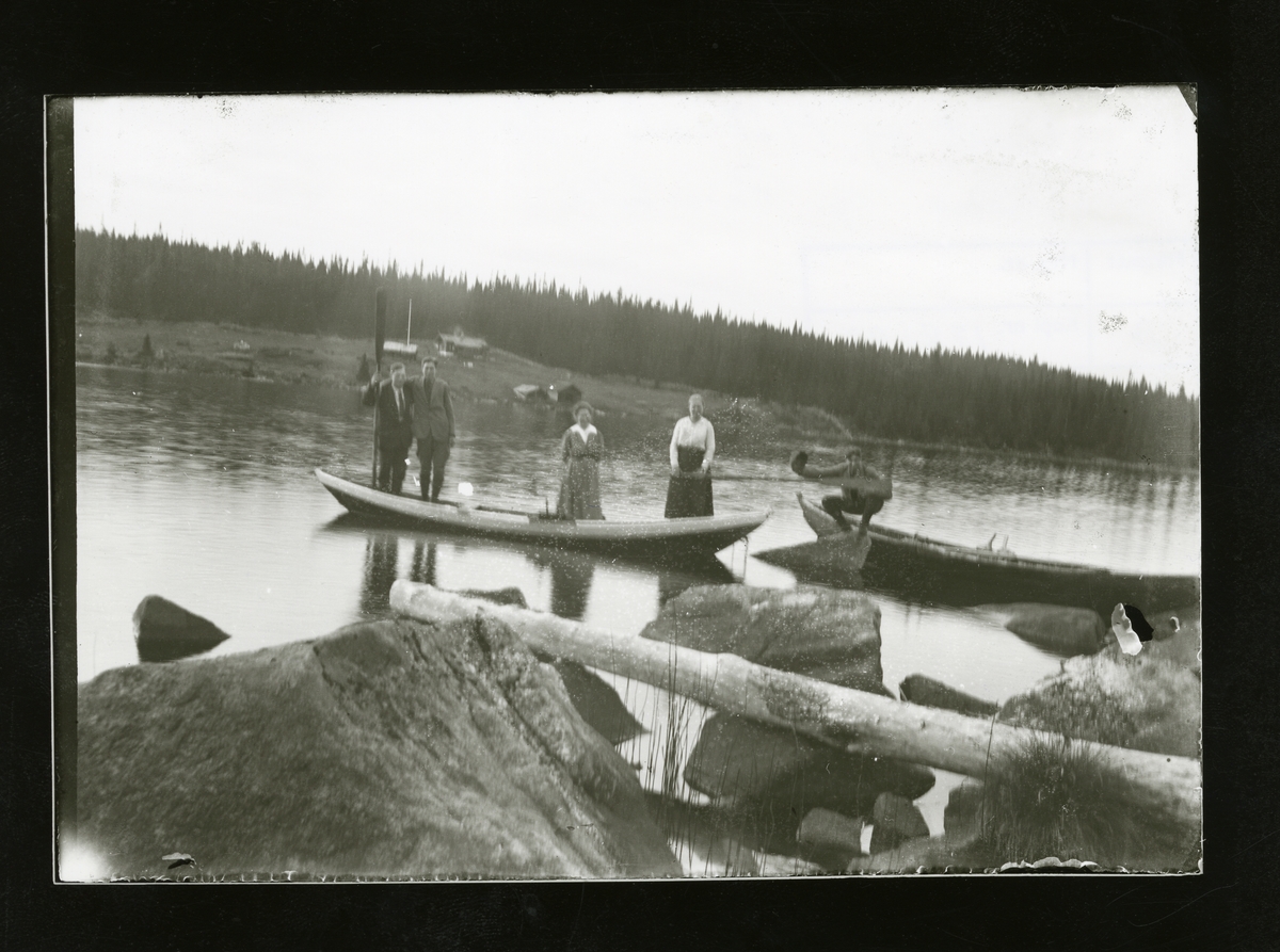 To kvinner og to menn står i en robåt på Høleravatnet. Solvangen i bakgrunnen.