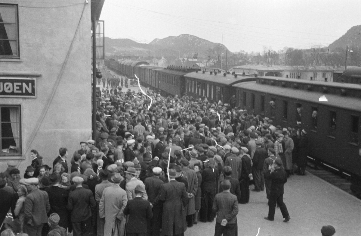 Stor folkemengde på jernbanestasjonen. Toget ser ut til å være på tur nordover. Kan det være Kongebesøk eller fanger som kommer hjem fra Fallstad? 
