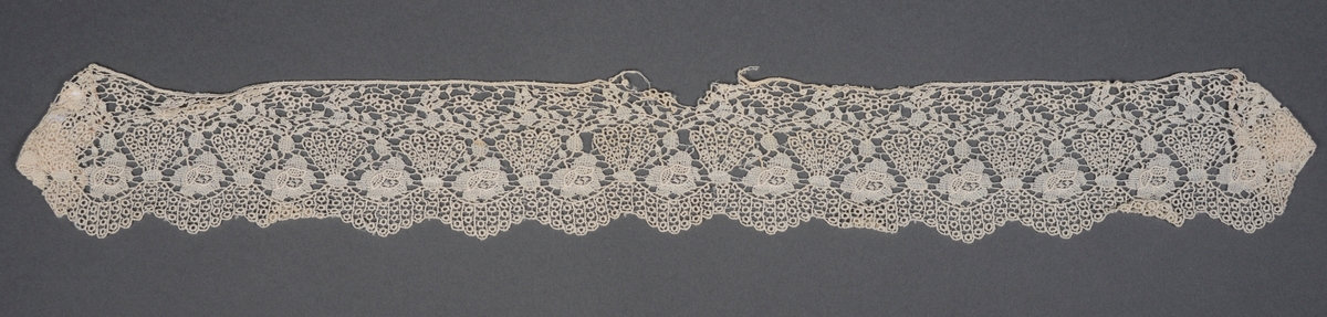 Kniplet blonde. Innsydd i begge ender, noe som gjør det sannsynlig å anta at det er brukt som gardinbånd.