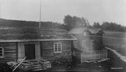 Stabbur, person, bolighus, gjerde.