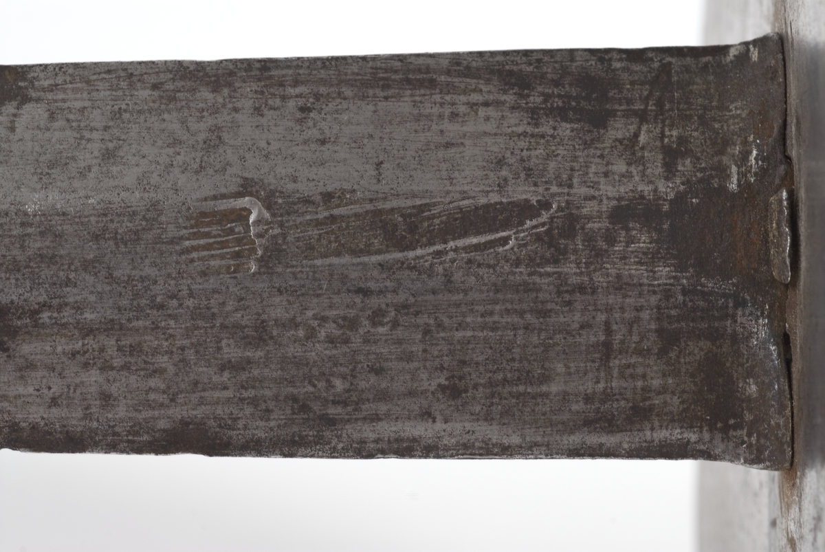 Dansk/Norsk Soldatkårde modell 1701. Plommeformet knapp med nitteknapp. Tregrep med messingtråds bevikling og hylse oppe og nede. Nyreformet parerplate med 5 fliker. Nedbøyd bakre parerstang. Fremre parerstang går over i håndbøylen og er tappet i knappen.
Rett tveegget klinge med 6 kantet tverrsnitt. Rester av etset dekor.