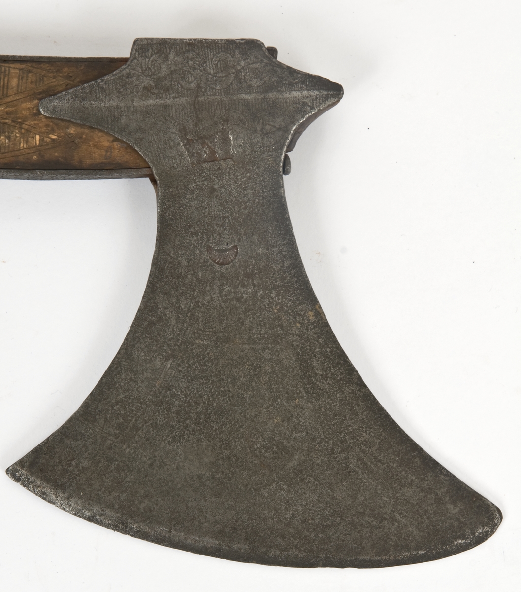 Asymmetrisk blad med lang øvre spiss og kortere nedre spiss.
Bladet er tynt, med påsmidd noe tykkere egg.
Øksehammeren har skaftehull og fliker.
Smedmerke formet som et skjell. Øksen har etset rankedekor på begge sider.
Skaftet er svakt krummet med skinner på rygg-og forside Skinnene har dekor i form av små halvmåner og S. Skaftet er merket ANNO 1758 THS. Skaftet har skåret dekor i felter. Skaftet har doppsko og pigg.