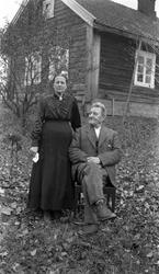 Uidentifisert mann og kvinne i helfigur utenfor et lite tømr